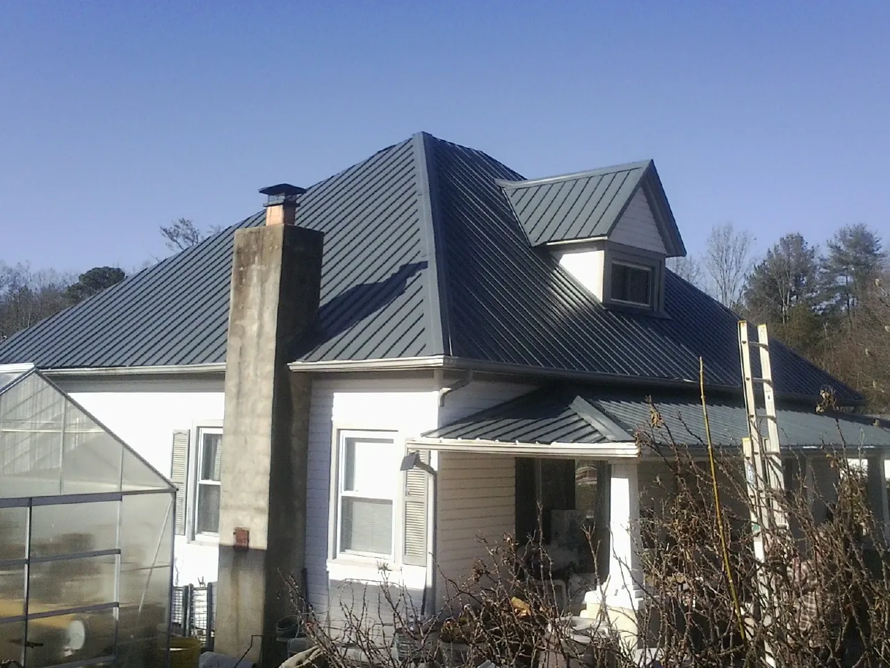 Dark blue standing seam metal roof on a white farmhouse with dormer — Slate & Tile Roof Repair by Roofing Brothers in Tyaskin