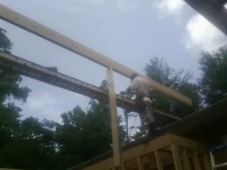 Carpenter setting a ridge beam over a new addition frame — Ice Dam Removal by Roofing Brothers in Tyaskin