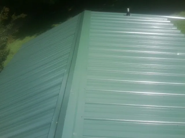 New green metal panels meeting at the ridge of a roof — Flat Roof Repair work by our crew in Tyaskin