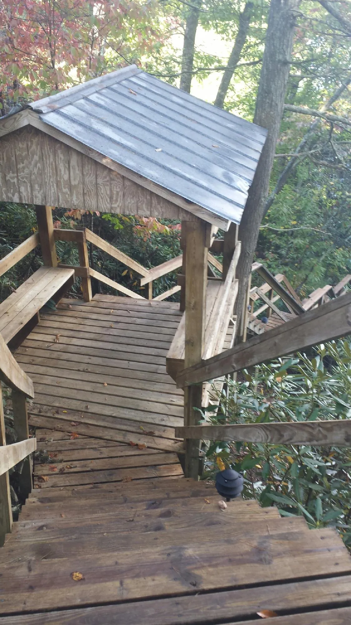 Metal roofed shelter over wooden steps on a wooded walkway — Skylight Repair & Installation work by our crew in Tyaskin