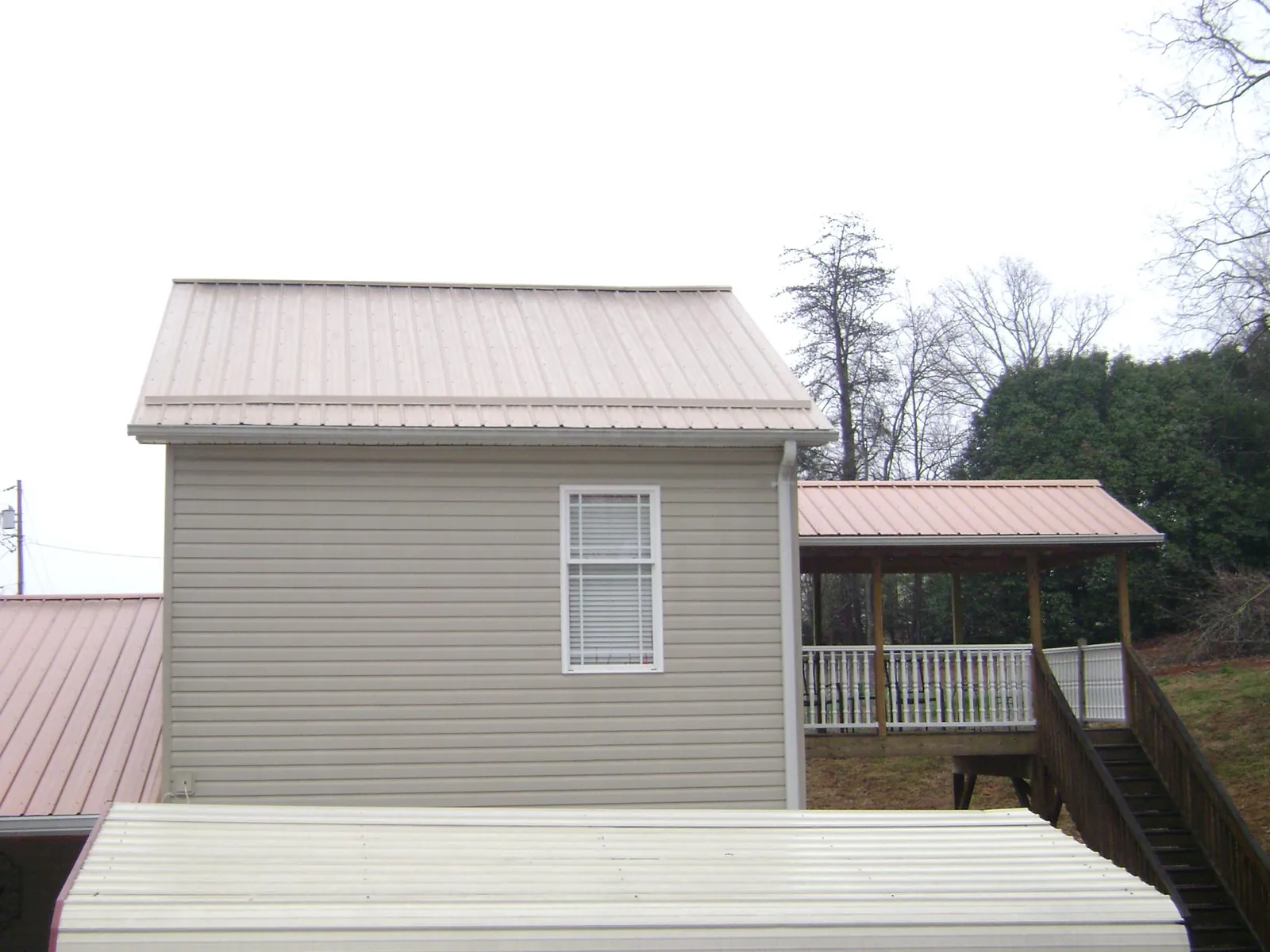 Tan metal roofs on a two story addition and attached porch, from a Roof Replacement job in Tyaskin